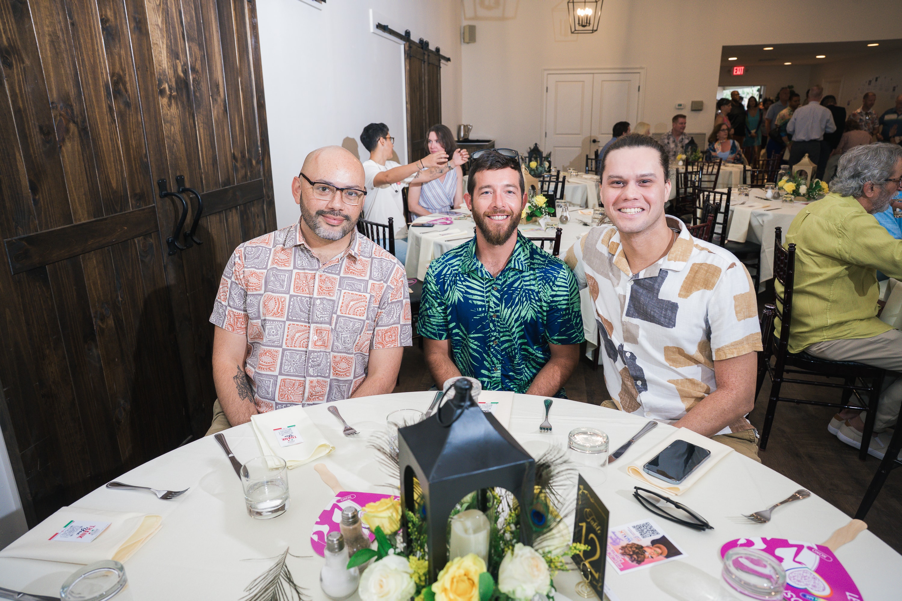 Three men smiling at their table at Peacocks & Divas 2025