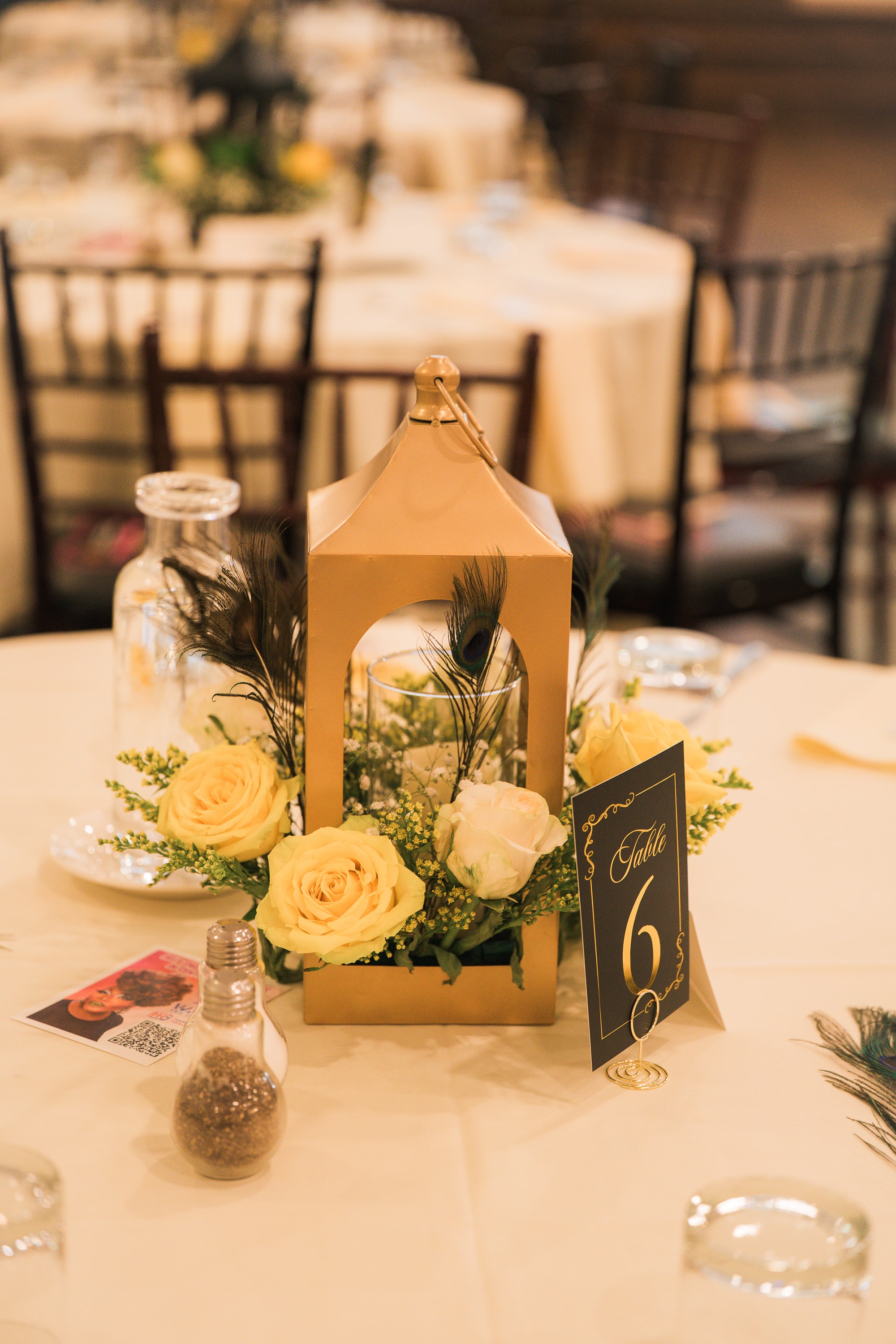 Gold lantern centerpiece with yellow roses at Peacocks & Divas 2025